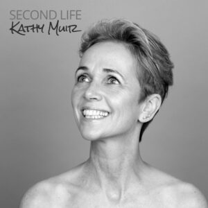 Black and white image of a woman bare from the shoulder up, looking to the left smiling.